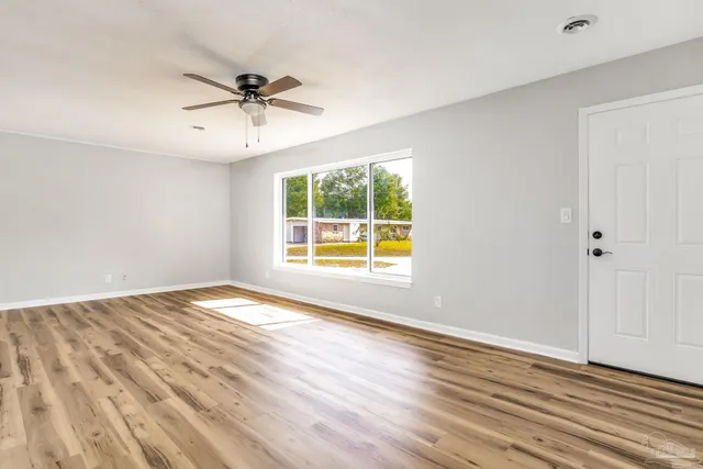 a view of an empty room with wooden floor and a window