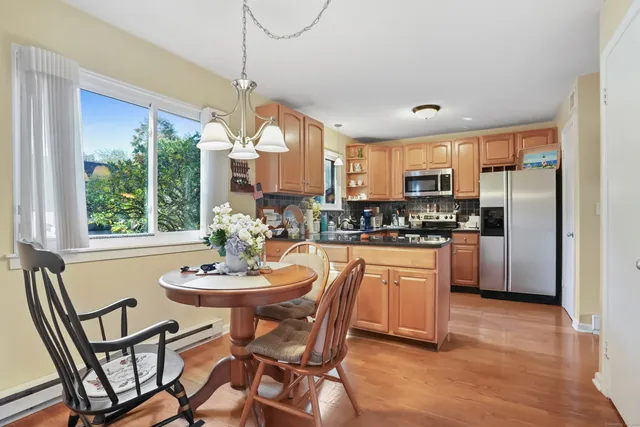 a kitchen with stainless steel appliances granite countertop a stove a refrigerator a kitchen island a table and chairs