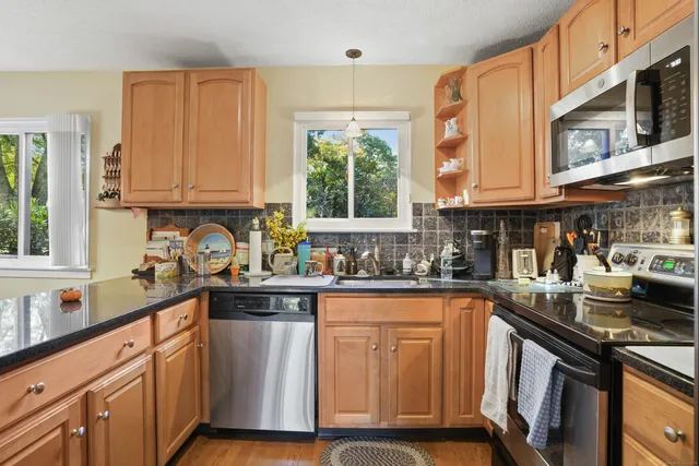 a kitchen with stainless steel appliances granite countertop a stove a sink dishwasher and cabinets with wooden floor