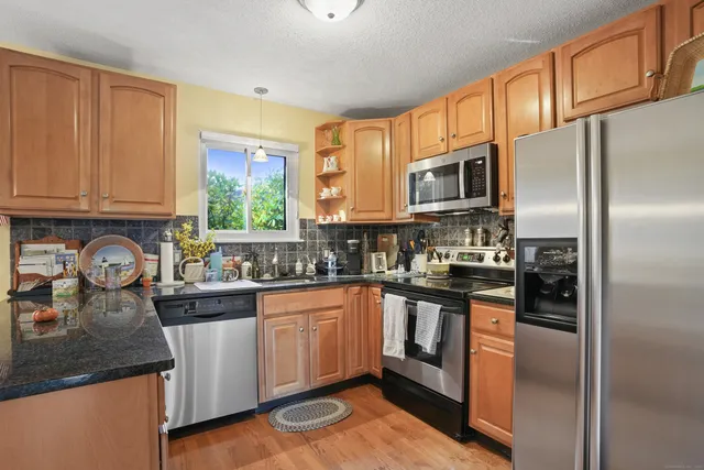 a kitchen with stainless steel appliances granite countertop a refrigerator a sink a stove and cabinets
