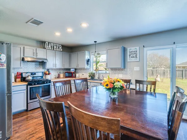 a kitchen with stainless steel appliances granite countertop a stove a refrigerator a dining table and chairs