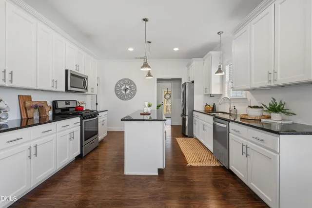 a large kitchen with stainless steel appliances granite countertop a stove a sink dishwasher and a refrigerator with wooden floor