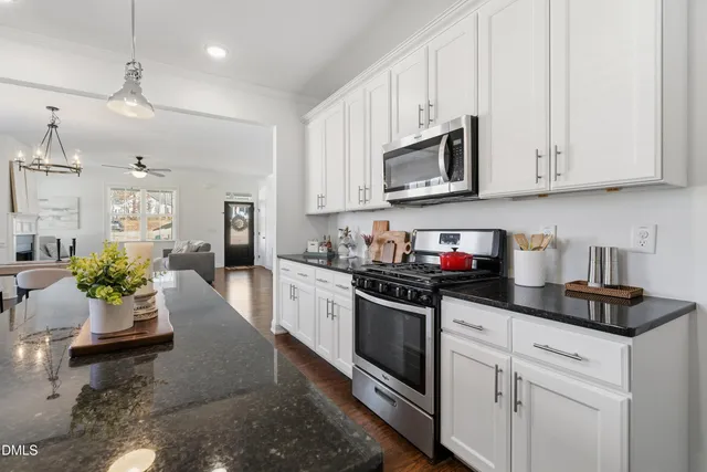a kitchen with stainless steel appliances granite countertop a sink dishwasher stove top oven and cabinets with wooden floor