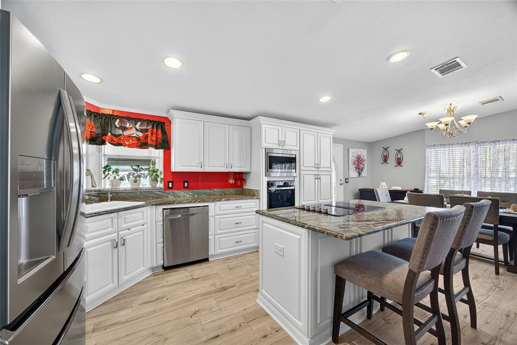 29221 Orangewood Street Punta Gorda, FL 33982 - Photo 8 of 38 a kitchen with stainless steel appliances granite countertop a kitchen island hardwood floor sink stove dining table and chairs