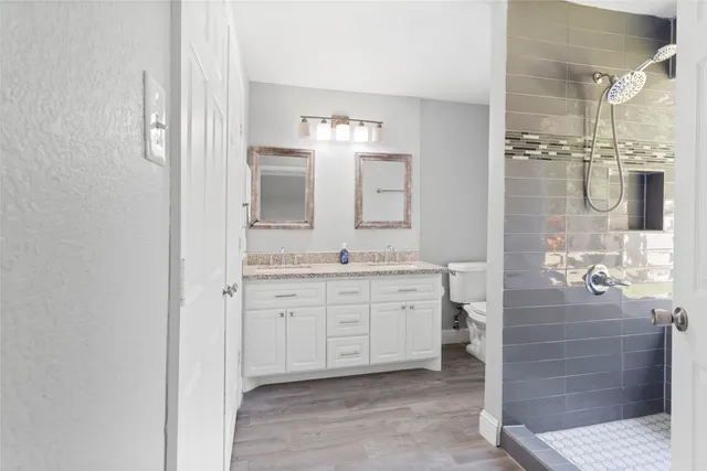 a spacious bathroom with a granite countertop sink a mirror and a shower