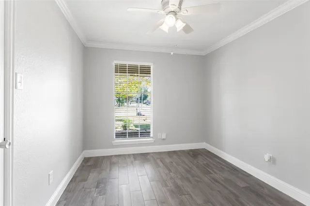 an empty room with wooden floor fan and windows