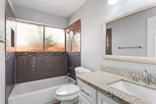 a bathroom with a granite countertop sink toilet and bathtub