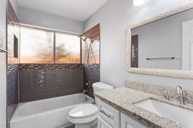 a bathroom with a granite countertop sink toilet and bathtub