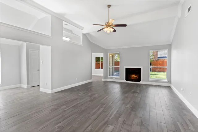 a view of an empty room with wooden floor fireplace and a window