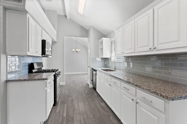 a kitchen with stainless steel appliances granite countertop a stove a sink and white cabinets
