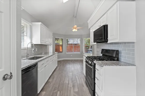 a large kitchen with a stove top oven a sink a microwave and wooden floor