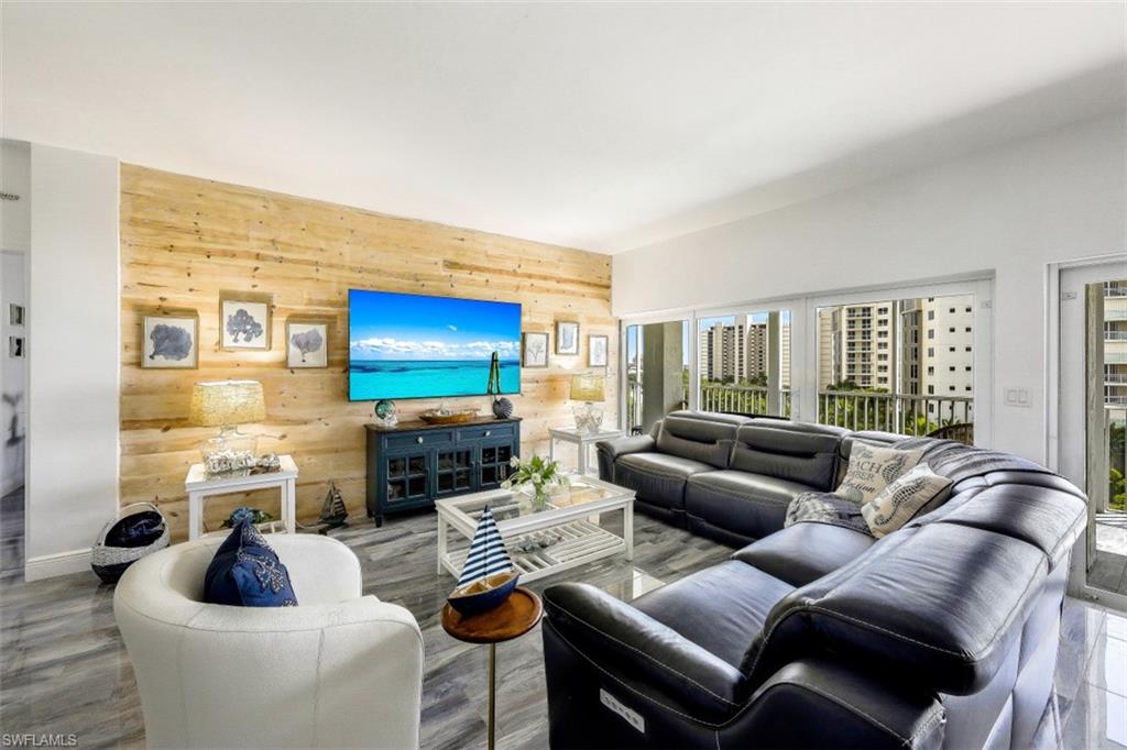 1 Bluebill Avenue, Unit 803 Naples, FL 34108 - Photo 5 of 19 a living room with furniture a large window and a flat screen tv