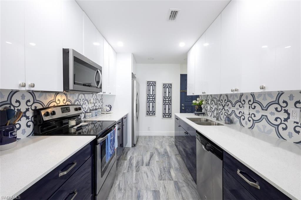 1 Bluebill Avenue, Unit 803 Naples, FL 34108 - Photo 8 of 19 a kitchen with granite countertop a sink stove and cabinets