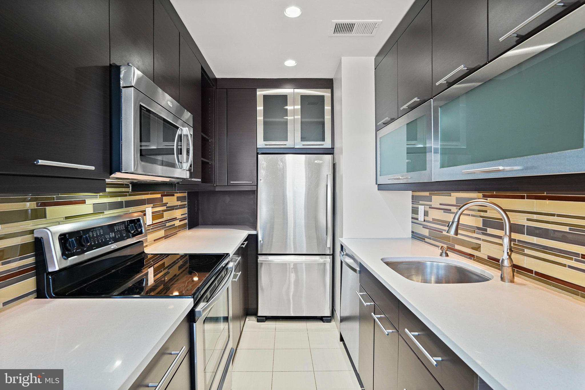 1920 S Street Northwest, Unit 804 Washington, DC 20009 - Photo 12 of 25 a kitchen with stainless steel appliances kitchen island granite countertop a refrigerator a stove and a sink with wooden cabinets
