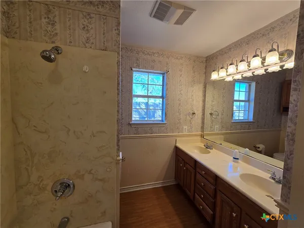 a bathroom with a double vanity sink a large mirror and shower