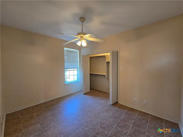 an empty room with chandelier fan and windows