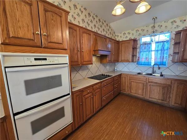 a kitchen with granite countertop wooden cabinets stainless steel appliances and a sink