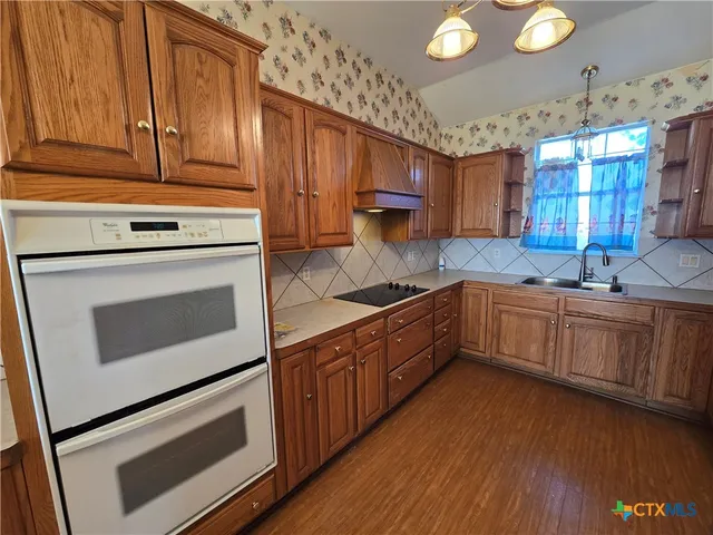 a kitchen with granite countertop wooden cabinets stainless steel appliances and a sink