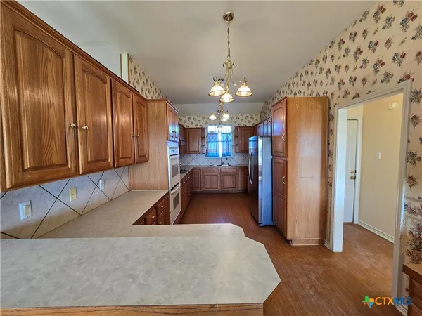 a living room with stainless steel appliances granite countertop furniture a couch and a chandelier