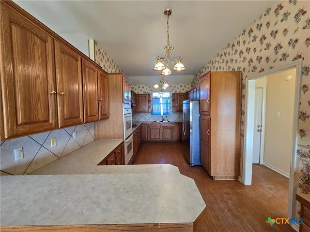 a living room with stainless steel appliances granite countertop furniture a couch and a chandelier