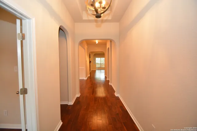 a view of a hallway with wooden floor and a chandelier