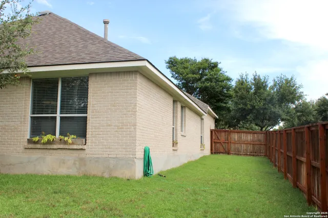 a view of an house with backyard space and wooden fence