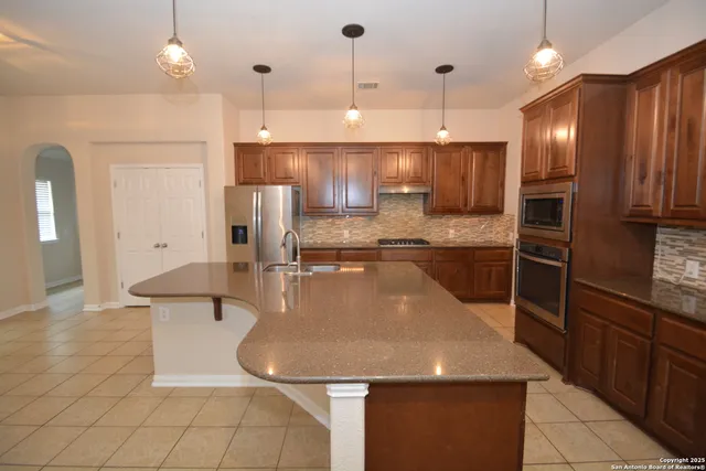 a kitchen with stainless steel appliances granite countertop a sink a stove and a refrigerator