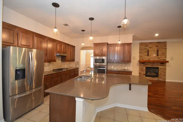 a kitchen with stainless steel appliances granite countertop a refrigerator a stove a sink a oven and a kitchen island