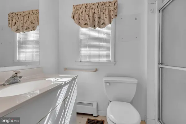 a bathroom with a granite countertop toilet a sink and a window