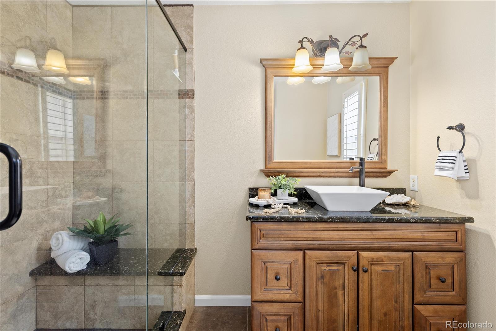 1468 Thunder Butte Road Castle Rock, CO 80109 - Photo 20 of 33 a bathroom with a granite countertop sink a mirror and vanity