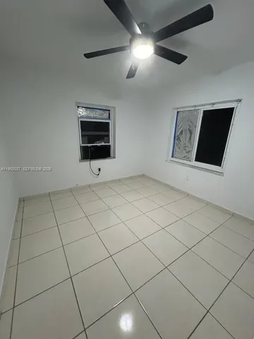 a view of an empty room with a ceiling fan and window