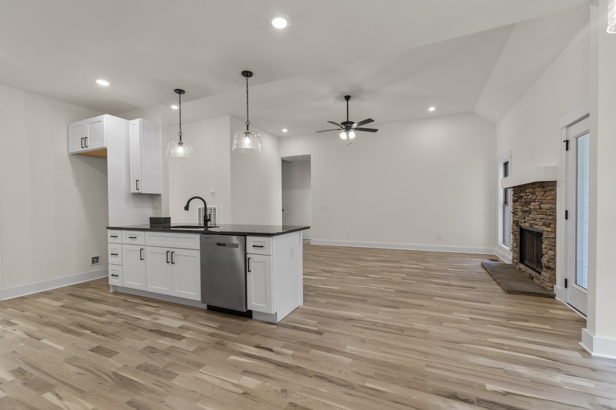 2969 Lights Chapel Road Greenbrier, TN 37073 - Photo 5 of 34 a large white kitchen with a refrigerator a sink dishwasher a fireplace and a dining table with wooden floor