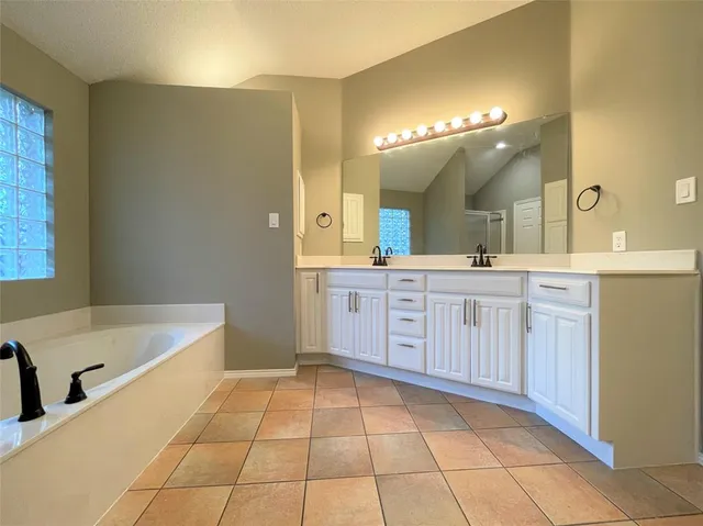 a spacious bathroom with a double vanity sink a mirror and a bathtub