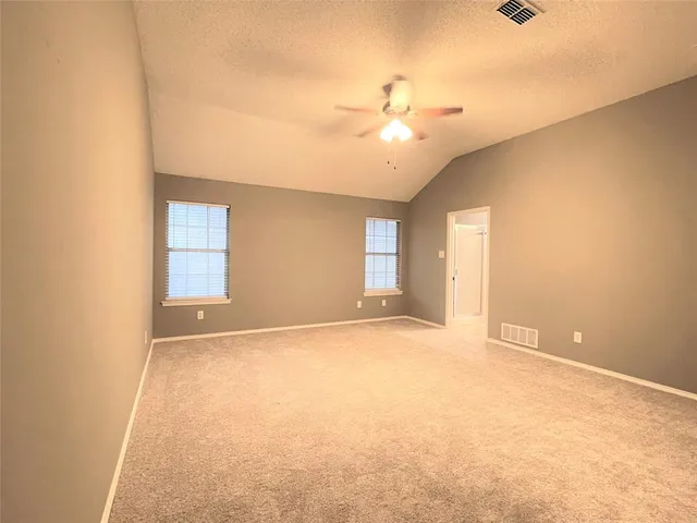 an empty room with a ceiling fan and window