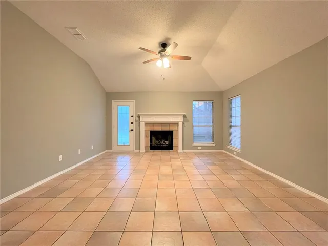 a view of an empty room with a fireplace and a chandelier fan