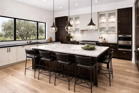 a kitchen with stainless steel appliances granite countertop a stove a refrigerator a sink a dining table and chairs with wooden floor