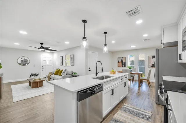 a kitchen with stainless steel appliances kitchen island granite countertop a dining table chairs and white cabinets