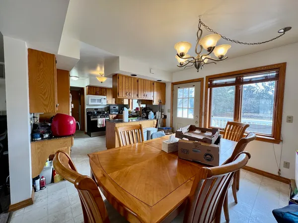 a view of a dining room with furniture a chandelier and large windows