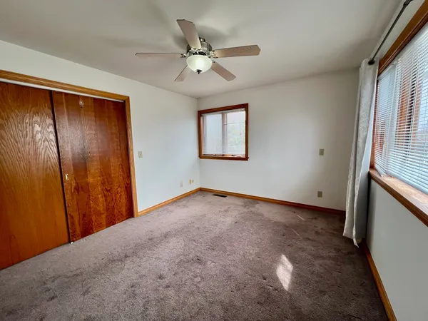 an empty room with fan and windows