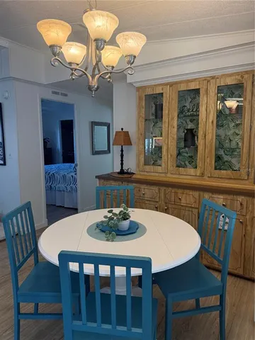a dining room with wooden floor a chandelier a wooden table and chairs