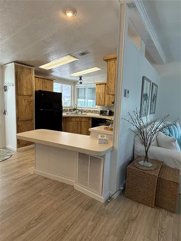 a living room with stainless steel appliances kitchen island granite countertop a refrigerator a stove and a wooden floors