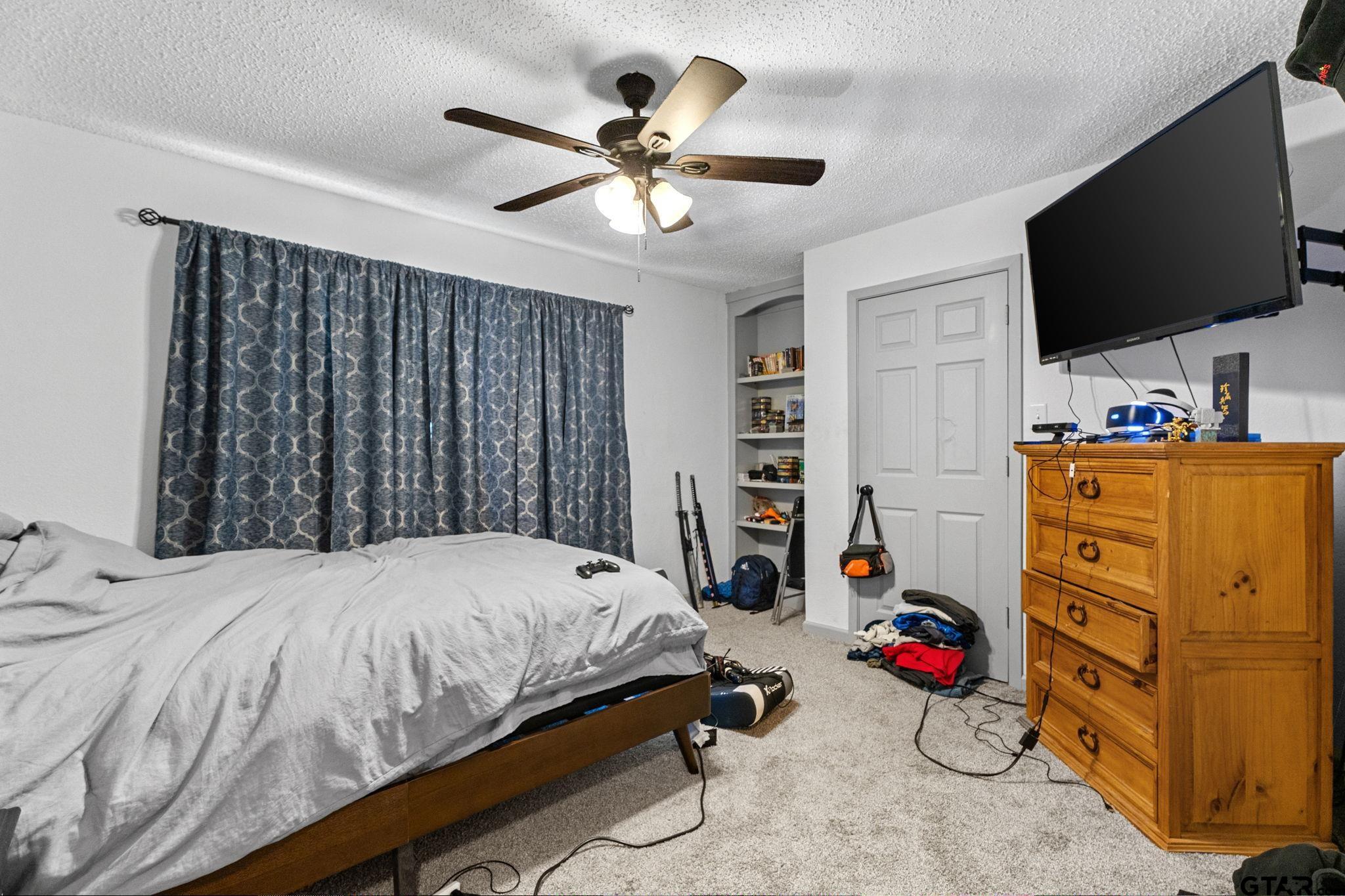 7649 Timber Circle Tyler, TX 75708 - Photo 14 of 25 a bedroom with a bed and a flat tv screen on dresser