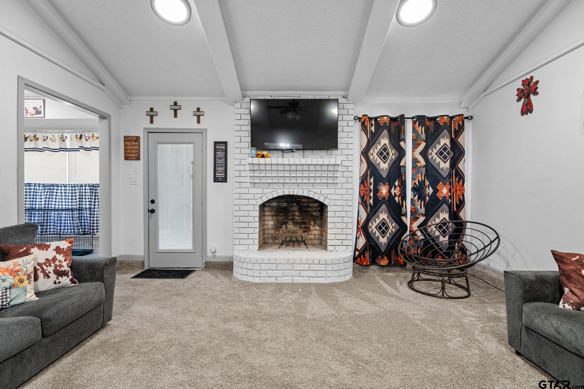 7649 Timber Circle Tyler, TX 75708 - Photo 5 of 25 a living room with furniture a flat screen tv and a fireplace