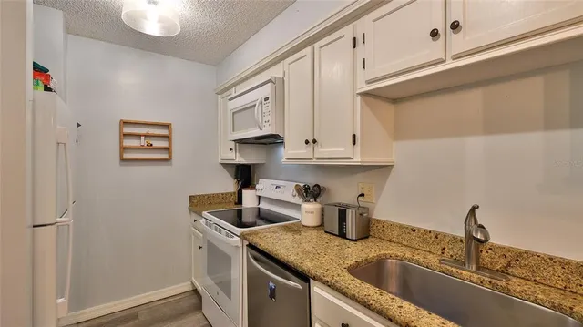a kitchen with stainless steel appliances granite countertop a sink and a white cabinets