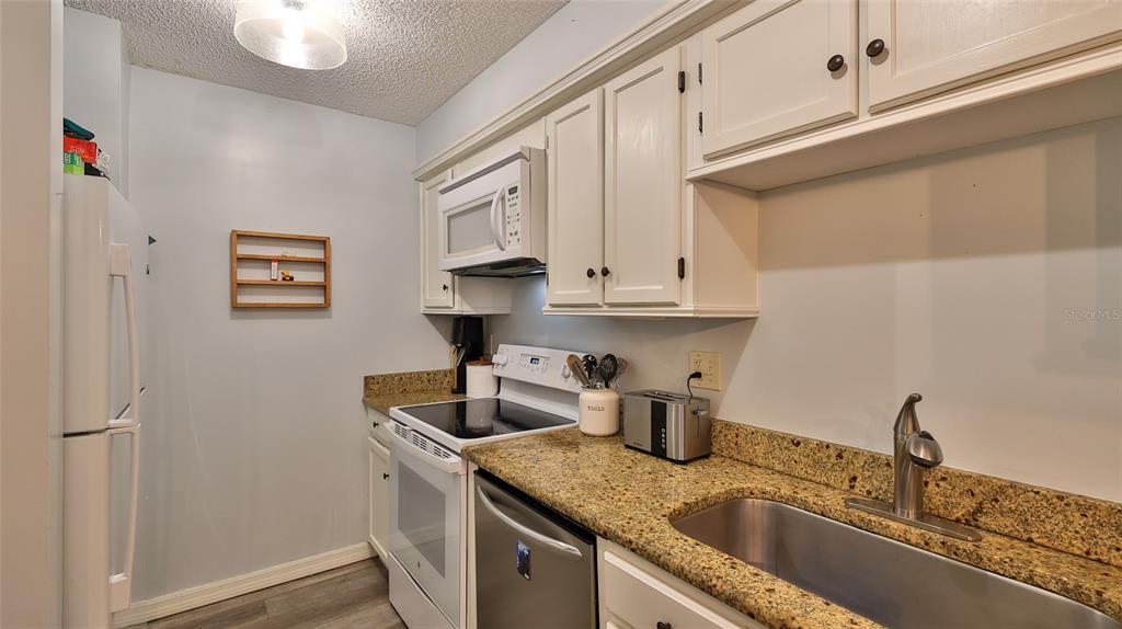 4740 South Atlantic Avenue, Unit 4 Ponce Inlet, FL 32127 - Photo 11 of 38 a kitchen with stainless steel appliances granite countertop a sink and a white cabinets