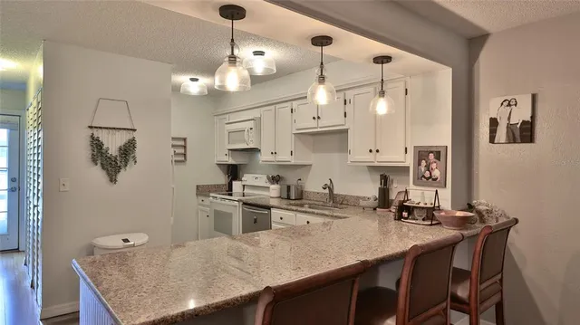 a kitchen with stainless steel appliances granite countertop a sink a stove a refrigerator a dining table and chairs