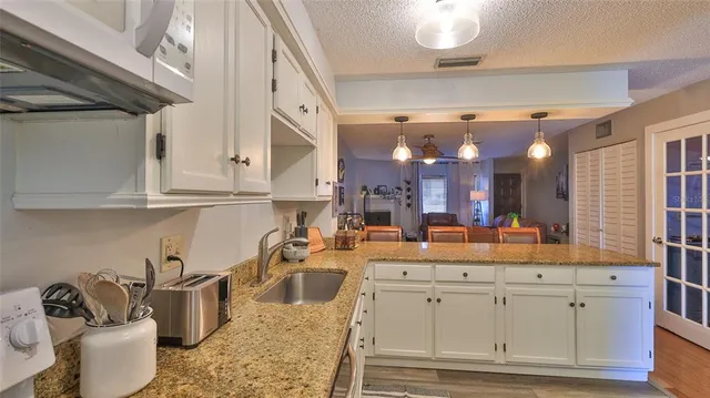 a kitchen with white cabinets and sink