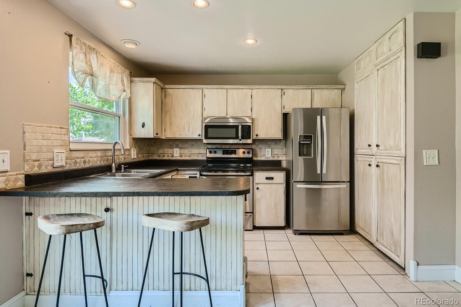11099 Fairfax Circle Thornton, CO 80233 - Photo 12 of 33 a kitchen with stainless steel appliances granite countertop a refrigerator a stove a sink and white cabinets with wooden floor