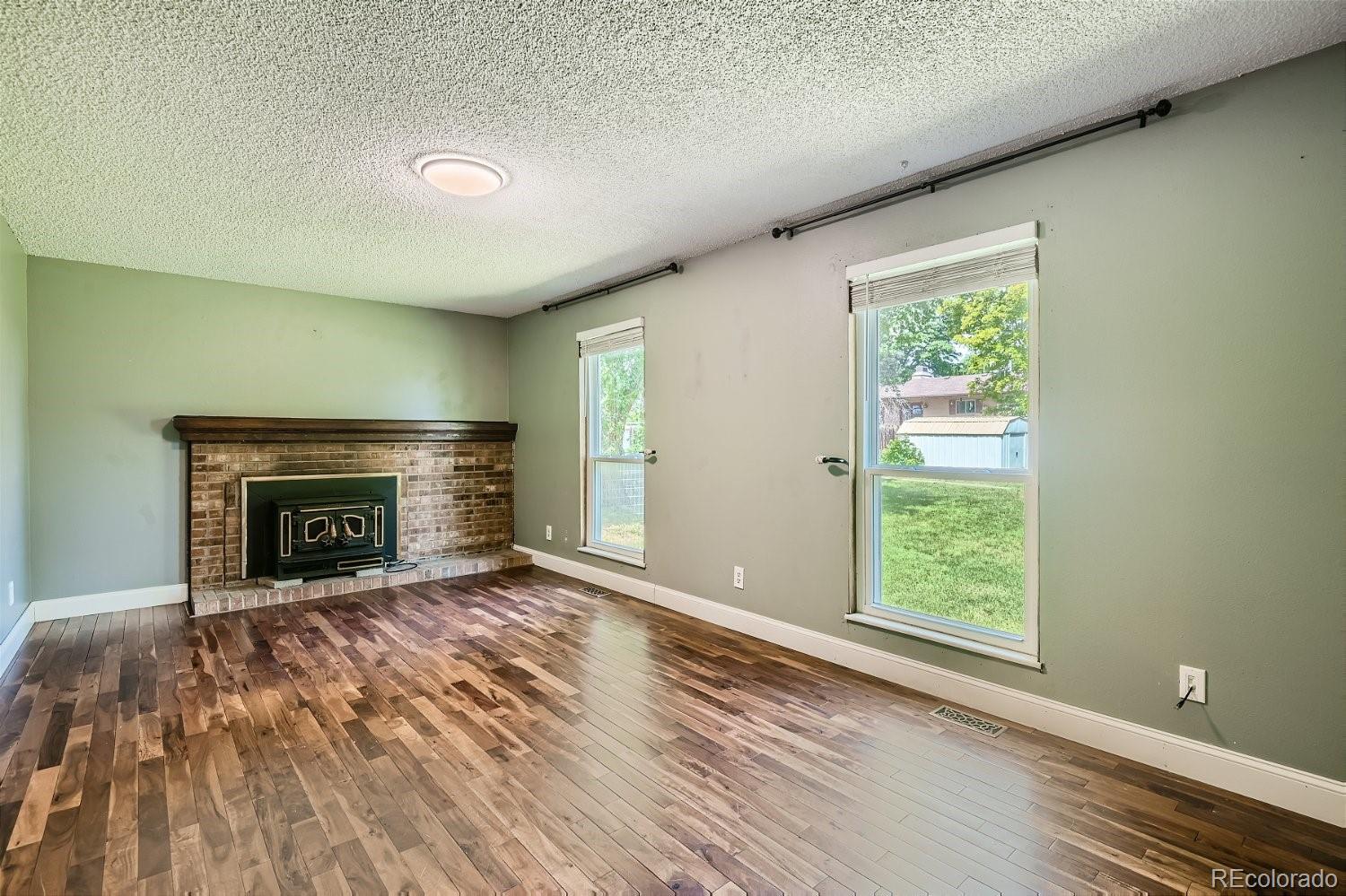 11099 Fairfax Circle Thornton, CO 80233 - Photo 15 of 33 a view of an empty room with wooden floor fireplace and a window