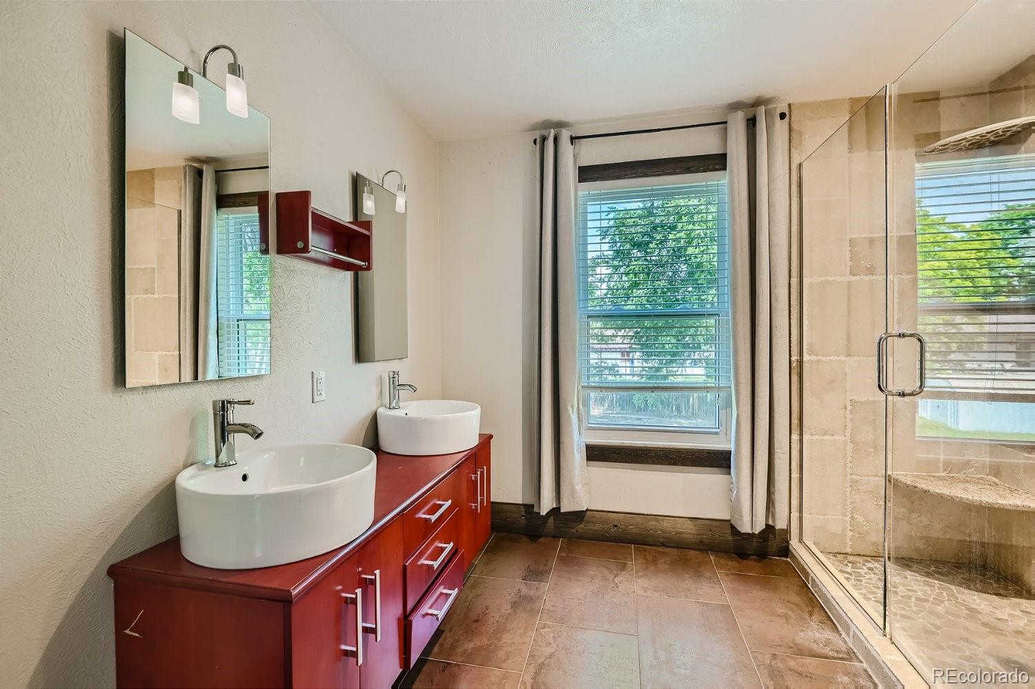 11099 Fairfax Circle Thornton, CO 80233 - Photo 22 of 33 a bathroom with a double vanity sink a mirror and a bathtub